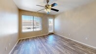 Located at 350 N Harrison Rd in Tucson, Arizona, this single-story home offers seven bedrooms and two full bathrooms within a well-utilized floor plan. The combined kitchen and living room serves as the central hub of the home, featuring wood-look plank flooring, a peninsula-style breakfast bar, and a fully equipped kitchen with white cabinetry accented by wood trim, white appliances including a refrigerator, range, microwave, and dishwasher. The open layout allows for a natural flow between cooking and living spaces. The bedrooms vary in finish, with the primary bedroom and select others featuring wood-look plank flooring and ceiling fans with light fixtures, while additional bedrooms are finished with wall-to-wall carpeting. Each bedroom benefits from natural light through large windows dressed with vertical blinds, offering views of the surrounding neighborhood. The two bathrooms are clean and functional, each equipped with a full tub-shower combination with chrome fixtures and white tile or surround walls. Two hallways connect the various rooms throughout the home, providing efficient circulation. The overall aesthetic is clean and neutral, with warm beige tones throughout, making it a practical and accommodating space.