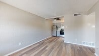This single-floor unit offers a practical and updated layout designed for comfortable everyday living. The main living area is open and welcoming, characterized by warm wood-look plank flooring, neutral-toned painted concrete block walls, and a textured ceiling. A ceiling fan provides both comfort and light, while a front entry door and adjacent window allow natural light to fill the space.

The kitchen flows seamlessly from the living area and is outfitted with stainless steel appliances, including a refrigerator, electric range, and dishwasher. Gray cabinetry with a classic tile backsplash and light countertops give the kitchen a clean, modern feel. A window above the sink brings in additional natural light.

The bedroom features the same wood-look flooring, painted concrete block accent walls, and a window overlooking the exterior. A dedicated closet with built-in hanging rod provides ample storage. The full bathroom is clean and functional, offering a single-sink vanity with storage, a toilet, and a shower/tub combination, all finished with wood-look flooring and a window for natural ventilation.

Throughout the unit, consistent flooring, neutral tones, and updated fixtures create a cohesive, move-in-ready atmosphere.