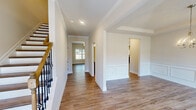 Located in Lawrenceville, GA, this well-appointed two-story home offers five bedrooms, three bathrooms, and a thoughtfully designed layout spread across two floors. The main level welcomes you with warm hardwood-style flooring, crown molding, and elegant wainscoting in the entry hallway and dining room, creating a polished first impression. The open flow connects the living room and dining area, ideal for everyday living and entertaining. The kitchen is a functional centerpiece, featuring dark espresso cabinetry, granite countertops, a subway tile backsplash, stainless steel appliances, and a window that brings in natural light. Upstairs, the spacious primary bedroom includes a generous walk-in closet with wire shelving systems and a private en-suite bathroom complete with granite vanity, a glass-enclosed shower, and a soaking tub. Four additional bedrooms are carpeted, well-lit by large windows with outdoor views, and served by two additional full bathrooms. Three closets throughout the home provide ample storage. A staircase with a classic wood and iron railing connects the floors with style. The overall ambiance is clean, bright, and move-in ready, with consistent finishes throughout.