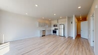 Located in the desirable NW 25th corridor of Portland, Oregon, this single-floor unit presents a clean, contemporary design with a cohesive aesthetic throughout. Light-toned luxury vinyl plank flooring runs continuously across the entire space, lending warmth and visual continuity from room to room.

The open-concept living and kitchen area is a standout feature, offering generous square footage and recessed lighting overhead. The kitchen is outfitted with white shaker-style cabinetry, light quartz countertops, and a full suite of stainless steel appliances including a refrigerator, electric range, over-the-range microwave, and dishwasher. The layout flows naturally into the living area, which benefits from large floor-to-ceiling windows and a glass panel door that flood the space with natural light and frame elevated views of the surrounding Portland cityscape and tree canopy.

The bedrooms are calm and well-proportioned, with neutral walls and windows that continue to capture the outdoor scenery. Two bathrooms serve the unit; one features a walk-in shower with white tile surround and a white vanity with ample cabinetry, while the second includes a full tub-shower combination and a matching vanity. Both bathrooms maintain the same light, clean palette found throughout the rest of the space, contributing to an overall sense of modern simplicity and functional design.