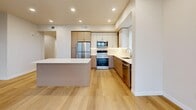 Located in Millcreek, Utah, this well-appointed 2-bedroom, 2-bathroom residence offers a clean, modern aesthetic throughout. Light-toned hardwood flooring runs consistently across the entire unit, lending a cohesive and airy feel to every room. The open-concept living, dining, and kitchen area serves as the heart of the home, bathed in natural light from large black-framed windows that frame views of the surrounding Millcreek neighborhood and distant mountains. The kitchen is outfitted with stainless steel appliances, a full suite of cabinetry in a warm two-tone palette of white and natural wood, a subway tile backsplash, and a central island with a white countertop ideal for casual dining or meal prep. Both bedrooms are generously proportioned, each featuring large windows with elevated city and mountain views, recessed lighting, and direct closet access. The two bathrooms mirror each other in design, each offering a tub-shower combination with white subway tile surround, brushed nickel fixtures, and built-in open shelving for added storage convenience. Connecting the rooms are well-lit hallways with louvered and panel doors. Additional features include an in-unit laundry room, a utility room, and a private balcony, completing this thoughtfully designed modern residence.