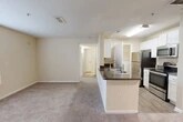 Located at 10010 Skinner Lake Dr in Jacksonville, Florida, this one-bedroom, one-bathroom residence offers a well-organized single-floor layout designed for comfortable everyday living. The open-concept living and dining area is finished with plush wall-to-wall carpeting and features a ceiling fan, creating a bright and airy atmosphere. A sliding glass door with adjacent window fills the space with natural light and provides direct access to a private balcony. The kitchen is equipped with stainless steel appliances — including a refrigerator, range, and microwave — complemented by white cabinetry, dark granite-style countertops, and a peninsula with a double stainless steel sink that opens to the main living area. Light wood-look flooring runs through the kitchen and extends into the in-unit laundry area, which houses a full-size washer and dryer. The hallway leads to the spacious bedroom, which features plush carpet, a ceiling fan with light, a large window with natural light, and access to multiple closets for generous storage. The bathroom offers a vanity with dark countertop, white cabinetry, tile flooring, and a full shower-tub combination. A dedicated utility room and additional closets throughout complete this efficiently designed home.