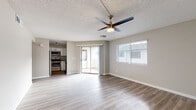This single-floor residence offers a clean, modern aesthetic with consistent light wood-style flooring running throughout every room. The open living area is bright and welcoming, featuring a textured ceiling, a ceiling fan with integrated lighting, and large windows fitted with blinds that allow natural light to fill the space. A sliding glass door connects the living area directly to an outdoor space, enhancing the sense of openness. The kitchen is thoughtfully updated with white shaker-style cabinetry, gray quartz countertops, a white subway tile backsplash, and a full suite of stainless steel appliances including an electric range, over-the-range microwave, and dishwasher. A single-basin stainless steel sink is positioned beneath a window. The bedrooms are generously sized, each equipped with ceiling fans and windows that bring in natural light. One bedroom features a textured ceiling, while another showcases a distinctive vaulted or stepped ceiling detail. The bathrooms are finished with white cabinetry, undermount sinks, and quartz-style countertops. One bathroom includes a glass-enclosed walk-in shower, while the other offers a full soaking tub and shower combination. The overall palette of warm neutral tones and crisp white trim creates a cohesive, move-in-ready environment.