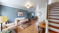 Located at 2967 Glenn Ave in Los Angeles, CA 90023, this two-story home offers a practical and comfortable layout spread across two floors. The main level features an inviting living room with warm hardwood flooring, crown molding, a classic ceiling fixture, and a distinctive blue accent wall that adds character to the space. A dining area flows naturally from the living room, making the floor plan feel open and connected. The kitchen is outfitted with white cabinetry, dark countertops, a double sink, and a gas range, providing a clean and efficient workspace. The upper floor hosts all three bedrooms, each finished with hardwood floors. The primary bedroom is a comfortable size and features an expansive wall of built-in white cabinetry offering generous storage. A second bedroom includes a ceiling fan, large window for natural light, and dark wood furnishings, while the third bedroom accommodates twin beds alongside a built-in closet. The shared full bathroom is finished in white with a tub-shower combination, pedestal sink, medicine cabinet mirror, and a frosted window for natural light. A staircase connects both levels, and the home maintains a cohesive, neutral color palette throughout with warm wood tones tying each room together.