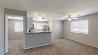 Located at 4500 Overland Dr in Lawrence, Kansas, this single-floor residence offers a well-designed, functional layout with a neutral color palette of soft grays and warm beige tones throughout. The open-concept living and dining area features plush wall-to-wall carpeting and a ceiling fan with light fixture, creating a comfortable and airy atmosphere. Multiple windows dressed with blinds allow natural light to fill the space, while a sliding glass door in one room opens to an outdoor view, further brightening the interior.

The kitchen is thoughtfully equipped with white cabinetry, stainless steel appliances including a refrigerator, electric range, dishwasher, and built-in microwave, complemented by light tile flooring and a peninsula counter that connects it to the living space. Additional bedrooms are generously sized, each featuring ceiling fans, carpeted floors, and windows that invite natural light.

The two full bathrooms are cleanly finished with tile flooring, white vanities with single-basin sinks, large mirrors, and tub-shower combinations. Ample closet access is visible throughout the floor plan, adding practical storage. The overall layout flows efficiently, making this a well-appointed and move-in ready residence.