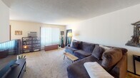 Located at 1435 Jessamine Ave W in Saint Paul, Minnesota, this single-floor unit offers a practical and comfortable layout across several well-defined living spaces. The living room is carpeted and generously sized, featuring a textured ceiling, vertical blind-covered windows that allow ample natural light, and enough space for a large sectional sofa and entertainment setup. The open sightlines create an inviting atmosphere well-suited for everyday living. The kitchen is equipped with white cabinetry, dark laminate countertops, a double stainless steel sink, and a dishwasher, providing functional workspace for meal preparation. The primary bedroom is carpeted and bright, benefiting from multiple windows with vertical blinds and drapes, and includes a ceiling fan with light fixture. A second bedroom offers carpeted flooring, vertical blinds, and a ceiling light, making it a versatile space suitable as a guest room or home office. An additional flex room with carpeted floors and a large window provides further adaptability. The full bathroom features tile flooring, a vanity with storage, a lighted mirror, and a shower-tub combination. Throughout the unit, neutral wall tones and consistent carpeting contribute to a cohesive and functional living environment.