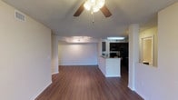 This single-floor residence offers a thoughtfully designed open-concept layout that seamlessly connects the living area to the kitchen. Rich hardwood-style flooring flows consistently throughout, complemented by neutral-toned walls and textured ceilings. The spacious living area is fitted with a ceiling fan with integrated lighting and a track lighting system, while a large sliding glass door opens to a private balcony with views of surrounding palm and shade trees, bringing in generous natural light.

The kitchen is well-equipped with dark espresso cabinetry, granite-style countertops, a double-basin stainless steel sink, and black appliances including a range, microwave, and refrigerator. A peninsula counter connects the kitchen to the living space, providing additional prep and dining space.

The bedrooms are generously sized, each featuring hardwood-style flooring and large windows that frame lush outdoor greenery. The primary bedroom includes a ceiling fan and direct balcony access. The bathroom is finished with dark cabinetry, granite-style countertops, a wide vanity mirror, and a full tub-shower combination with tiled surround. The overall ambiance is clean, modern, and bright, making for a comfortable and functional living environment.