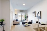 This thoughtfully designed one-bedroom, one-bathroom unit in Edmonton's southwest is arranged across a single floor, offering an efficient and well-organized layout. Light wood flooring runs throughout, lending warmth and visual continuity to the space.

The living room is bright and inviting, anchored by large windows and a balcony-facing sliding door that frames open views of the surrounding neighbourhood and fills the room with natural light. The kitchen is galley-style, featuring stainless steel appliances including a refrigerator, electric range, and over-the-range microwave, complemented by white cabinetry, stone-look countertops, and a grey tile backsplash.

The bedroom is a calm, neutral-toned retreat with a sizeable window overlooking the balcony and the broader cityscape beyond, providing natural light and an open feel. A dedicated closet and hallway offer practical storage and circulation between rooms.

The bathroom is finished with a white vanity topped with stone-look countertops, a full soaker tub with a grey tile surround extending to the ceiling, and the same light wood-style flooring found throughout the unit. The overall design palette is clean and contemporary, emphasizing neutral tones, modern fixtures, and functional use of space.
