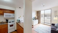 Located on Fifth Street in Santa Monica, California, this single-floor unit offers a practical and well-organized layout with distinct living, sleeping, cooking, and bathing areas. The interior features light wood flooring throughout, contributing to a warm, cohesive aesthetic across the space.

The kitchen is efficiently designed with warm-toned wood cabinetry, granite-style countertops, white appliances including an electric range, microwave, and refrigerator, as well as a sink and ample storage. A pass-through counter connects the kitchen to the adjacent living area, enhancing the open feel between spaces.

The living area is bright and functional, anchored by a large sliding glass door that allows natural light to filter in and provides views of the surrounding exterior. Neutral walls and draping curtains add a calm, understated ambiance to the room.

The bedroom is a quiet, comfortable space with wood flooring, a window bringing in natural light, and clean white walls. The full bathroom includes a combination tub and shower, a wood-toned vanity, and tile flooring, offering a simple and functional design.

Overall, the unit presents a clean, neutral palette with practical finishes suited for everyday living in a prime Santa Monica location.