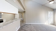 This single-floor residence offers a thoughtfully designed layout with a clean, neutral color palette throughout. The living area is a standout feature, boasting soaring vaulted ceilings that create an expansive, airy atmosphere. Plush carpeting covers the living and bedroom floors, while hard-surface flooring runs through the kitchen and connecting hallway. A glass-paneled exterior door allows natural light to pour into the living space, adding warmth and a connection to the outdoors.

The kitchen is efficiently designed and well-equipped with stainless steel appliances, including a refrigerator and electric range, complemented by white cabinetry, granite-style countertops, and a stylish mosaic tile backsplash. A breakfast bar provides a casual dining option. Conveniently located within the kitchen area, a stacked washer and dryer unit offers in-unit laundry.

The bedrooms are generously sized, each featuring soft carpeting, neutral walls, and ample natural light from window blinds. Closet storage is available with bifold doors. The bathroom includes a full tub-shower combination in a clean, bright finish. Throughout the space, white trim and baseboards provide a crisp, finished look that ties the overall design together cohesively.