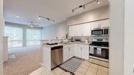 This single-story residence offers a thoughtfully designed layout across a compact yet functional floor plan. The combined kitchen and living area serves as the heart of the home, where an open-concept design promotes a sense of spaciousness. The kitchen is equipped with white shaker-style cabinetry, granite countertops, a peninsula with a built-in sink and dishwasher, and a full suite of stainless steel appliances including a range, microwave, and refrigerator. Track lighting overhead provides focused illumination throughout the cooking space, while tile flooring adds durability underfoot.

The living area transitions seamlessly from the kitchen, featuring plush carpeting, a ceiling fan, a wood-burning fireplace with a classic white mantle, and large windows that invite abundant natural light and outdoor views. A hallway connects the main living space to the private bedroom and bathroom. The bedroom is a comfortable retreat finished with soft carpet, a ceiling fan, and a window for natural light. The full bathroom features tile flooring, a granite-topped vanity with white cabinetry, and a tub-shower combination with tiled surround. Neutral tones and clean finishes are consistent throughout the entire residence.