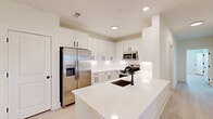 Located in Kathleen, GA, this single-story, 3-bedroom, 2-bathroom home offers a bright and modern living experience with a clean, contemporary design throughout. Light wood-look flooring flows seamlessly across the open-concept layout, complemented by crisp white walls and flush lighting that create an airy, welcoming ambiance.

The kitchen is a standout feature, showcasing floor-to-ceiling white shaker cabinetry with matte black hardware, a large center island with an undermount sink and striking white quartz countertops, and stainless steel appliances including a French door refrigerator with ice maker and a built-in microwave. The space is both functional and visually cohesive.

The spacious primary bedroom features a ceiling fan, access to a private ensuite bathroom, and a dedicated closet. Two additional bedrooms are well-proportioned, each with ceiling fans and windows that invite natural light. Both bathrooms are finished with white subway-tiled tub-shower combinations and matte black fixtures for a modern touch.

A dedicated laundry room provides added convenience with utility hookups and built-in wire shelving above. Three closets throughout the home offer ample storage. The overall design is clean, minimal, and move-in ready, making this home a practical and stylish choice in the Kathleen area.