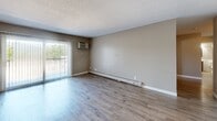 Located at 520 James Ave in Mankato, MN, this 2-bedroom, 1-bathroom unit offers a practical and well-appointed single-floor layout. The living area features hardwood-style flooring, a textured ceiling, and a sliding glass door that opens to a balcony, filling the space with natural light. Baseboard heating runs throughout, and a wall-mounted AC unit in the living room provides year-round comfort. The galley-style kitchen is a standout feature, lined with rich dark wood cabinetry, granite-look countertops, a classic white subway tile backsplash, and stainless steel appliances including a range and refrigerator. Wood-look flooring and overhead lighting complete the kitchen's functional design. Both bedrooms are carpeted and feature neutral-toned walls, windows with vertical blinds that bring in natural light, and open closets with built-in shelving and hanging rods for ample storage. The spacious primary bedroom offers a generous footprint. The bathroom is cleanly finished with tile wainscoting, a dark wood vanity with a white sink, wood-look tile flooring, and a full tub-shower combination. A hallway connects the rooms, finished with the same hardwood-style flooring found in the main living areas.