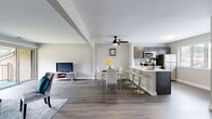 This single-floor residence offers a thoughtfully designed open-concept layout that seamlessly connects the living, dining, and kitchen areas. Rich wood-look flooring flows throughout the main living spaces, complemented by neutral gray walls and a ceiling fan that enhances both style and comfort.

The kitchen is a standout feature, outfitted with dark gray shaker-style cabinetry, crisp white countertops, a subway tile backsplash, and a full suite of stainless steel appliances including a gas range, microwave, and refrigerator. A peninsula with bar seating provides additional counter space and a casual dining option, while a separate dining area accommodates a full table and chairs.

The living room offers a calm, welcoming atmosphere with access to an outdoor balcony, allowing natural light to fill the space. Two well-sized bedrooms are finished with plush carpeting and large windows that bring in ample daylight. Each bedroom includes closet storage, and the primary bedroom features dual closets.

The bathroom is finished with wood-look tile flooring and a mosaic tile surround in the tub and shower area, adding a refined touch. A conveniently located in-unit laundry closet houses a stacked washer and dryer, adding everyday practicality to this comfortable and modern home.