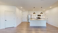 Located at 200 Aycock Avenue in Monroe, GA, this single-story 2-bedroom, 2-bathroom home offers a thoughtfully designed open-concept layout with modern finishes throughout. The kitchen serves as the heart of the home, featuring a central island with a granite countertop, undermount sink, and striking black pendant lighting. White shaker-style cabinetry, a white subway tile backsplash, and stainless steel appliances — including a range, microwave, and refrigerator — complete the space, along with a convenient walk-in pantry. The kitchen flows seamlessly into the living area, which is bathed in natural light from large windows and a glass door, and is finished with wood-look flooring and a ceiling fan. Both bedrooms are bright and spacious, featuring wood-look flooring, large windows with blinds, and ceiling fans. The generously sized primary bedroom connects to an en-suite bathroom with a dual-sink vanity, granite countertops, and white cabinetry. A large walk-in closet with wire shelving provides ample storage. The second bedroom and additional bathroom offer equally well-appointed accommodations. Clean white walls and consistent wood-look flooring tie the entire home together in a cohesive, contemporary aesthetic.