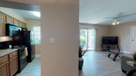 Located on Eden Isle Boulevard in Saint Petersburg, Florida, this single-floor residence offers a well-designed, open layout filled with natural light. Light wood-style flooring runs throughout the main living areas, creating a clean and cohesive aesthetic.

The living room is a welcoming space anchored by a tufted teal leather sofa, complemented by contemporary accent tables and a large abstract wall canvas. Sliding glass doors face lush greenery, allowing natural light to flow freely into the room. A ceiling fan adds to the comfort of the space.

Adjacent to the living area, a compact dining nook provides an intimate setting with a dark wood table and modern upholstered chairs, accented by tasteful wall art.

The galley-style kitchen is efficiently laid out with warm wood cabinetry, granite-look countertops, black appliances including a range, refrigerator, and dishwasher, and a window overlooking greenery.

The bedroom is a tranquil retreat featuring plush carpet, a substantial wood headboard with coordinating nightstands and dresser, a ceiling fan, and framed botanical artwork that lends a coastal charm.

The bathroom includes a single vanity with granite-look countertops, rich wood cabinetry, and a tub-shower combination, offering a clean and functional design throughout.