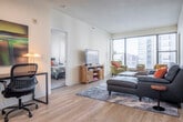 Located in the heart of Madison, WI on East Wilson Street, this well-appointed 2-bedroom, 2-bathroom residence offers a thoughtfully designed single-floor layout that maximizes both comfort and functionality. Light wood-style flooring flows throughout the main living areas, complementing the clean, modern aesthetic of the space.

The open-concept living room is bathed in natural light from large windows that frame urban city views, creating a bright and welcoming atmosphere. A peninsula-style kitchen features light maple cabinetry, white quartz countertops, stainless steel appliances including a refrigerator, range, microwave, and dishwasher, and a breakfast bar with seating — ideal for casual dining and entertaining.

Both bedrooms are carpeted for comfort and include windows with city views. The generously sized primary bedroom offers ample room and direct access to its own bathroom. The two bathrooms are finished with light maple vanity cabinetry, white countertops, and tile flooring, with one bathroom offering additional built-in linen storage.

A dedicated closet provides practical storage, while the overall layout ensures a smooth and intuitive flow between rooms. The combination of contemporary finishes, abundant natural light, and a central Madison location makes this residence a compelling urban living option.