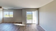 Located at 1 Spyglass Pkwy in Vallejo, CA, Unit 1102 is a single-floor residence that combines contemporary design with functional living spaces. The galley-style kitchen is a standout feature, outfitted with dark espresso cabinetry, brushed chrome hardware, light quartz countertops, a stainless steel sink, and a full suite of stainless steel appliances including a range, microwave, and refrigerator. Wood-look flooring runs throughout the main living areas, adding warmth and continuity to the space. The open living area is filled with natural light, thanks to a large sliding glass door that opens to an outdoor patio and frames a striking waterfront view — a defining characteristic of this unit. A secondary window also brings in additional natural light. The bedroom features plush carpeting, a generous closet with louvered bi-fold doors, and a window overlooking the surrounding grounds. The bathroom is clean and efficiently designed, with a full soaking tub, shower combination, and chrome fixtures set against neutral, textured walls. Throughout the unit, a soft gray-toned color palette creates a calm, cohesive ambiance that complements the scenic surroundings.