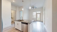 Located at 9779 Fannin Railway in Houston, TX, this single-floor, two-bedroom, two-bathroom unit offers a thoughtfully arranged layout that maximizes its compact footprint. The open-concept kitchen serves as the heart of the space, boasting white shaker cabinetry, granite countertops, a subway tile backsplash, and stainless steel appliances including a refrigerator with ice maker, electric range, and over-the-range microwave. A central island with a built-in sink and pendant lighting above provides additional workspace and casual dining potential. Light wood-look flooring flows throughout the main living and kitchen areas, contributing to a clean, contemporary aesthetic.

Both bedrooms feature plush carpeting and tall windows fitted with horizontal blinds, allowing ample natural light while offering exterior views. The elevated window design adds a sense of height to each room. Each bedroom includes a dedicated closet, with the primary bedroom offering a walk-in closet with built-in shelving and hanging rods for organized storage.

The bathrooms are finished with granite-topped vanities, white cabinetry, and light wood-look flooring. One bathroom features a soaking tub with tile surround. The overall ambiance is bright, neutral, and move-in ready.