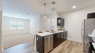 Located at 3111 Hayden Rd in Columbus, Ohio, this well-appointed 2-bedroom, 3-bathroom residence offers a thoughtfully designed single-floor layout. The open-concept living and kitchen area serves as the heart of the home, where light-toned luxury vinyl plank flooring flows seamlessly underfoot. The kitchen is a standout feature, boasting dark espresso cabinetry, crisp quartz countertops, stainless steel appliances including a refrigerator, range, microwave, and dishwasher, and a central island illuminated by two globe pendant lights with gold accents — ideal for both meal prep and casual dining. The adjoining living area transitions to plush carpeting and receives natural light through a window overlooking the exterior. Both bedrooms are carpeted and offer a clean, neutral palette with natural light from windows with blinds. The primary bedroom is generously sized and includes a walk-in closet fitted with wire shelving and hanging rods. The three bathrooms are finished with dark vanity cabinetry, quartz countertops, and LVP flooring, with tub/shower combinations. A dedicated laundry area and hallway add to the functional layout of this modern, move-in-ready home.