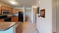 Located at 5005 W Equestrian Pl in Sioux Falls, South Dakota, this single-floor residence offers a comfortable and functional layout designed for everyday living. The kitchen features light oak cabinetry, dark laminate countertops, and black appliances, including a full-size refrigerator, with a breakfast bar that opens toward the main living area. Soft, neutral-toned carpet flows throughout the living spaces, creating a warm and cohesive atmosphere. The spacious living room is a standout, centered around a large sliding glass door that opens to a private balcony, flooding the room with natural light and offering pleasant outdoor views of the surrounding greenery and neighboring buildings. A ceiling fan adds both comfort and style to the living area. The two bedrooms are well-proportioned and carpeted, each featuring windows that allow natural light to filter in, with the larger bedroom offering a particularly bright and airy feel. The bathroom is finished with tile flooring, a wood-framed vanity with ample storage, a well-lit mirror, and a full tub-shower combination. Textured ceilings are consistent throughout the home, adding a classic residential character. The overall ambiance is calm, neutral, and move-in ready.