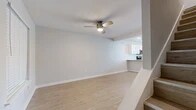 This two-story home offers a clean, modern aesthetic with a thoughtfully organized layout spread across two floors. The main level houses the open-concept living room and kitchen area, finished with light wood-style flooring and neutral gray walls that create a bright, airy feel. A ceiling fan with integrated lighting anchors the living room, which features a teal front entry door adding a distinctive pop of color. The kitchen is well-appointed with white shaker-style cabinetry, a white subway tile backsplash, stainless steel appliances including a refrigerator, range, and over-the-range microwave, and a peninsula countertop with a built-in sink — ideal for both cooking and casual dining. A window above the kitchen brings in natural light.

Upstairs, two bedrooms each feature light wood flooring, ceiling fans, and windows with blinds for natural light and privacy. The primary bedroom includes a dedicated closet, while the second bedroom offers access to a hallway with built-in shelving. Both bathrooms are well-finished — one features a full soaking tub with large-format marble-style tile surround and a built-in niche, while the second serves as a half bath. Two closets and a staircase complete the interior, delivering practical storage and seamless vertical connectivity throughout the home.
