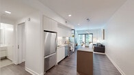Located in the vibrant Cathedral Heights neighborhood of Washington, DC, this thoughtfully designed one-bedroom, two-bathroom residence offers a sleek, modern aesthetic throughout. The open-concept layout seamlessly connects the kitchen, dining, and living areas, creating an efficient yet airy feel.

The gourmet kitchen is a standout feature, boasting floor-to-ceiling white cabinetry, stainless steel appliances including a Bosch range and French door refrigerator, a white quartz countertop, under-cabinet lighting, and a central island with a contrasting warm-toned finish — ideal for both meal prep and casual dining.

The living area is bright and inviting, anchored by large floor-to-ceiling windows that frame outdoor greenery and flood the space with natural light. Dark hardwood flooring runs throughout, providing a rich contrast to the clean white walls and ceilings.

The bedroom is a serene retreat, featuring oversized windows with outdoor views, a ceiling fan, and ample closet space. Both bathrooms are finished in a minimalist style, with the primary bath offering a glass-enclosed walk-in shower, floating vanity, and large-format neutral tile flooring. A dedicated closet and two hallways complete the well-organized floor plan.