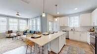 This single-story residence is designed with a modern, open-concept layout that promotes a seamless flow between living spaces. The kitchen serves as a central hub, featuring white shaker-style cabinetry, light quartz countertops, a subway tile backsplash, and a full suite of stainless steel appliances, including a dishwasher, range, and microwave. A large island with bar seating and pendant lighting extends into the dining area, creating a natural gathering space. The adjacent living area is bathed in natural light from a bank of large windows that frame outdoor views, complemented by light wood-style flooring that runs throughout the common areas.

The bedrooms are comfortably sized, each featuring plush carpet, natural light from well-positioned windows, and ceiling fans for year-round comfort. The bathrooms are finished in neutral tones with wood-style flooring, a tub-shower combination with shiplap-style surround, and classic white fixtures. A dedicated laundry closet in the hallway houses a stacked washer and dryer unit, adding practical convenience. A two-panel interior door with brushed nickel hardware is consistent throughout. The overall ambiance is bright, clean, and contemporary.
