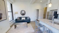 This 1-bedroom, 1-bathroom residence is thoughtfully laid out across a single floor, combining comfort and modern design. The open-concept living and dining area serves as the heart of the home, featuring light hardwood-style flooring, crisp white walls, and exposed beam detailing along the ceiling that adds a subtle architectural character to the space. Natural light fills the room, enhancing the clean and airy ambiance. The living area provides ample space for relaxing and entertaining, flowing seamlessly into the kitchen zone, which is equipped with a granite or stone-topped breakfast bar with seating — ideal for casual dining. The kitchen area connects effortlessly to the rest of the living space, reinforcing the open and inviting layout. A closet conveniently positioned off the main living area offers practical storage solutions. The bedroom and bathroom complete the unit, providing private and functional retreats. Throughout the residence, the design palette remains neutral and contemporary, with modern fixtures and finishes that create a cohesive, polished look. This unit is well-suited for those seeking a comfortable, efficiently designed living space with stylish touches.