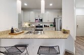 This 1,080-square-foot, single-story apartment at 3455 Kearny Villa Rd in San Diego's Tramonto community offers a well-designed 2-bedroom, 2-bathroom floor plan with contemporary finishes throughout. Wood-style flooring runs throughout the entire unit, providing a cohesive and low-maintenance aesthetic.

The open-concept kitchen and living area serves as the heart of the home. The kitchen features granite countertops, soft-gray shaker cabinetry with matte black hardware, stainless steel appliances including a gas range, microwave, refrigerator, and dishwasher, and a peninsula breakfast bar with pendant lighting. The adjoining living room is bright and spacious, with a sliding glass door leading to a private balcony with outdoor seating.

The primary bedroom spans 140 square feet and includes a ceiling fan, natural light from large windows, and access to a walk-in closet with built-in shelving and hanging rods. The en-suite primary bathroom features dual granite-topped vanities, a soaking tub-shower combo, and wood-style flooring. The second bedroom is equally well-appointed with ample natural light. The second full bathroom mirrors the clean, modern design with a tub-shower combo and granite vanity. Two hallways and an additional closet provide generous storage throughout the unit.