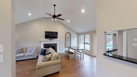 Located in Knoxville, Tennessee, this single-story community clubhouse offers a thoughtfully designed gathering space with a range of amenities suited for both relaxation and recreation. The centerpiece of the facility is a spacious great room featuring soaring vaulted ceilings and rich hardwood flooring. A classic white-mantled fireplace with slate surround anchors the room, while a ceiling fan and recessed lighting provide comfort throughout. Large windows and glass French doors flood the space with natural light and offer direct views of the outdoor pool area, creating a seamless indoor-outdoor connection. A dining area with a farmhouse-style table and benches sits adjacent to the great room, providing additional gathering space. A secondary lounge area with vaulted ceilings, hardwood floors, and ample seating offers a quieter retreat within the facility. The clubhouse also includes a functional kitchenette equipped with dark granite countertops, a double sink, dishwasher, and microwave — ideal for hosting events. A dedicated fitness center, enclosed by full glass walls, houses multiple cardio machines and mirrors, providing a bright and motivating workout environment. The overall design balances comfort and practicality, making this clubhouse a versatile community hub.