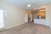 This single-floor residence at The Bristol in Memphis, Tennessee offers a well-organized layout with a blend of hardwood and carpeted flooring throughout. The kitchen serves as a central feature, equipped with stainless steel appliances including a refrigerator and over-the-range microwave, a black electric range, and a dishwasher. Light maple cabinetry provides ample storage, while granite countertops extend to a peninsula that opens toward the living area, creating an efficient and connected space. Track lighting illuminates the kitchen, enhancing its functionality. Rich hardwood flooring runs through the kitchen and entry areas, adding warmth and visual contrast to the neutral wall tones. The carpeted rooms are generously proportioned, each featuring French doors with slatted blinds that invite natural light and provide access to outdoor views. A ceiling fan is present in one of the carpeted rooms, contributing to the space's comfort. The entry area connects seamlessly to the kitchen and living zones, creating a logical and practical flow throughout the unit. Overall, the space maintains a clean, neutral palette that allows for flexible interior arrangement and personalization.