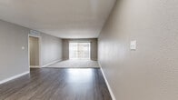 This single-floor residence offers 3 bedrooms and 4 bathrooms within a thoughtfully designed layout. The open living area is highlighted by a combination of dark hardwood-style flooring and plush carpet, with a sliding glass door that floods the space with natural light and provides access to an outdoor area. A secondary living space features light-toned wood flooring, recessed lighting, and a front entry door, with a glimpse into a kitchen adorned with white cabinetry and tile backsplash. The bedrooms are carpeted for comfort, with one featuring a ceiling fan, a bright window with exterior views, and another offering dual closets with louvered bifold doors, providing generous storage. The bathrooms are well-finished, featuring granite-topped vanities with grey cabinetry, wood-look tile flooring, and full tub-shower combinations clad in large-format stone-look tile with built-in niches. A connecting hallway ties the spaces together efficiently. The overall color palette of warm neutrals and grey tones gives the home a cohesive, modern, and welcoming ambiance throughout.