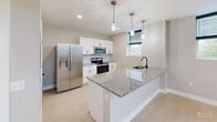 Located at 343 W Fourth St in Williamsport, PA, this thoughtfully designed one-bedroom, one-bathroom unit offers a clean, modern aesthetic across a single floor. The open-concept living and dining area flows seamlessly into a well-appointed kitchen, which features white shaker cabinetry with black hardware, granite countertops, a peninsula island with a undermount sink, pendant lighting, and a full suite of stainless steel appliances including a range, microwave, dishwasher, and refrigerator. Light wood-look flooring runs throughout the main living areas, complementing the neutral gray palette on the walls. Multiple windows allow natural light to filter in, with views of the surrounding neighborhood. The bedroom is a comfortable size, offering a ceiling fan, recessed lighting, and two double-door closets for ample storage. An additional hallway closet and utility and laundry rooms add practical convenience. The bathroom features light tile flooring, a vanity with a granite countertop, and a clean, minimalist design. A distinctive exposed ductwork element runs through the space, lending an industrial-modern character. Three closets total ensure generous storage throughout this efficiently designed home.