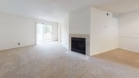 Located at 2 Wyndham Dr in Hampton, Virginia, this single-floor residence offers a thoughtfully arranged layout with a clean, neutral aesthetic throughout. The living area is generously proportioned, anchored by a tile-surround fireplace that serves as a natural focal point. Sliding glass doors lead to a private balcony, filling the space with natural light and providing outdoor views. Soft wall-to-wall carpeting runs throughout the living and bedroom areas, lending a warm and comfortable feel.

The bedroom is well-sized and benefits from dual windows and its own sliding glass door access to the balcony, along with a ceiling fan for year-round comfort. The kitchen features warm honey-toned cabinetry, dark speckled countertops, a double-basin stainless steel sink, and black appliances including a dishwasher and refrigerator, complemented by easy-care hard surface flooring. A dedicated dining or flex area adjacent to the kitchen adds versatility to the floor plan.

The bathroom is finished with stone-look tile flooring, a wood-toned vanity with a white countertop, and a full tub and shower with white tile surround. A convenient in-unit stacked washer and dryer is tucked into a dedicated laundry area, adding everyday practicality to this well-appointed home.