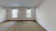 Located at 1668 Sassafras Ct in Kent, Ohio, this single-floor, two-bedroom, two-bathroom home offers a functional and straightforward layout. The living room is a generous, open space with neutral carpet flooring, a textured ceiling, and multiple windows that invite natural light and views of the surrounding greenery. A wood-panel entry door anchors the room. The kitchen features a galley-style design with white cabinetry, granite-style countertops, a double sink, and black appliances, including a refrigerator and range. Distinctive hexagonal terracotta-style tile flooring adds character to the kitchen and carries through into both bathrooms. The primary bedroom is notably spacious, offering carpet flooring, a large double bifold closet with warm wood-tone doors, and a private en-suite bathroom. The second bedroom is also carpeted and well-sized, featuring its own built-in double closet. Both bathrooms are finished with the same hexagonal tile flooring. The full bathroom includes a shower-tub combination with white surround, while the second bathroom offers a vanity with a marble-style countertop. Throughout the home, warm wood-tone door trim and accents provide a cohesive design element.