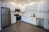 Located at 2004 City Vista Way in Knoxville, Tennessee, this single-floor space offers a clean, modern aesthetic defined by consistent design choices and quality finishes. Polished concrete flooring runs through much of the unit, lending an industrial yet refined character to the interiors.

The kitchen is a standout feature, outfitted with crisp white cabinetry accented by matte black hardware, white quartz countertops, and a full suite of stainless steel appliances including a refrigerator, electric range, microwave, and dishwasher. Open shelving adds both practicality and visual interest, while recessed and track lighting ensures the space is well-illuminated.

The living area is bright and airy, benefiting from tall ceilings, a sleek ceiling fan, and large windows that invite generous natural light. The open layout provides a versatile and comfortable living environment.

The bathroom continues the modern theme with white cabinetry, a quartz vanity top, matte black fixtures and hardware, and a glass-enclosed walk-in shower. Recessed lighting and a well-placed vanity light fixture complete the polished look.

Throughout the space, the design maintains a cohesive palette of white walls, neutral flooring, and dark accent hardware, creating a contemporary and move-in-ready environment in a conveniently located Knoxville address.