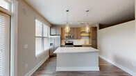 Located at 2895 Crescent Pkwy in Atlanta, GA, this one-bedroom, one-bathroom unit offers a well-designed single-floor layout that maximizes every square foot. The open-concept kitchen serves as a central highlight, featuring warm wood cabinetry, a classic subway tile backsplash, stainless steel appliances including a refrigerator with ice maker, electric range, and microwave, as well as a sleek white kitchen island illuminated by two elegant glass pendant lights. Natural light flows in through multiple windows fitted with blinds, enhancing the bright and airy atmosphere throughout. Hardwood-style flooring runs through the main living and kitchen areas, lending a clean, contemporary feel. A hallway connects the main living space to the private bedroom, which is carpeted for comfort and includes a ceiling fan. An adjacent closet provides dedicated storage. The bathroom is well-appointed with a vanity featuring a light stone countertop, a framed mirror, and a tiled tub-shower combination. Crown molding and clean white trim detailing throughout the unit contribute to a polished, modern aesthetic, making this a practical and stylish residence in the Atlanta area.