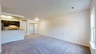The Fox is a one-bedroom, one-bathroom upgraded unit contained on a single floor, offering a well-organized and functional layout. The open floor plan, visible in the dollhouse view, connects the main living area to the kitchen, with the bedroom tucked toward the rear for privacy.

The living area is spacious and finished with plush wall-to-wall carpeting in a neutral gray tone. Clean white walls and a ceiling-mounted light fixture keep the space bright, while a mirrored sliding closet door adds depth. The bedroom is similarly carpeted and features a window that allows natural light and outdoor views, creating a comfortable and airy feel. Additional doors in the bedroom provide closet and hallway access.

The galley-style kitchen is a standout feature of this upgraded unit, finished with rich dark cabinetry paired with light countertops for contrast. Wood-look luxury vinyl plank flooring runs the length of the kitchen, which is equipped with stainless steel appliances including a gas range, refrigerator, and dishwasher. A double-basin sink with a modern faucet completes the functional workspace. The overall aesthetic is clean, contemporary, and move-in ready.