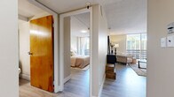 Located at 415 P St in Sacramento's vibrant Midtown district, this one-bedroom, one-bathroom residence offers a thoughtfully organized single-floor layout. Light wood-style flooring flows throughout, creating a cohesive and airy feel across all rooms.

The living room is a welcoming space anchored by a large floor-to-ceiling window that fills the room with natural light and offers views of the surrounding urban environment. The open layout comfortably accommodates a seating area and provides a relaxed atmosphere for everyday living.

The kitchen features crisp white cabinetry extending to the upper walls, offering generous storage, complemented by a full-size refrigerator, an electric range, and a double basin sink. A dining area adjacent to the kitchen provides a convenient space for meals.

A hallway connects the living areas to the private bedroom, which is a well-proportioned retreat featuring a large warm-toned wood wardrobe with bifold doors, a window with access to an outdoor balcony, and soft neutral wall tones that contribute to a calm ambiance.

The bathroom is equipped with a full tub-shower combination with tile surround, a vanity with an oak cabinet base, and a well-lit mirror. Throughout the unit, textured ceilings and neutral warm tones create a consistent, livable aesthetic suited to everyday comfort.