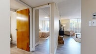 Located at 415 P St in Sacramento's vibrant Midtown district, this one-bedroom, one-bathroom residence offers a thoughtfully organized single-floor layout. Light wood-style flooring flows throughout, creating a cohesive and airy feel across all rooms.

The living room is a welcoming space anchored by a large floor-to-ceiling window that fills the room with natural light and offers views of the surrounding urban environment. The open layout comfortably accommodates a seating area and provides a relaxed atmosphere for everyday living.

The kitchen features crisp white cabinetry extending to the upper walls, offering generous storage, complemented by a full-size refrigerator, an electric range, and a double basin sink. A dining area adjacent to the kitchen provides a convenient space for meals.

A hallway connects the living areas to the private bedroom, which is a well-proportioned retreat featuring a large warm-toned wood wardrobe with bifold doors, a window with access to an outdoor balcony, and soft neutral wall tones that contribute to a calm ambiance.

The bathroom is equipped with a full tub-shower combination with tile surround, a vanity with an oak cabinet base, and a well-lit mirror. Throughout the unit, textured ceilings and neutral warm tones create a consistent, livable aesthetic suited to everyday comfort.