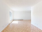 This well-appointed 2-bedroom, 1-bathroom unit at 390 Boul De La Cote Vertu offers a thoughtfully designed single-floor layout. The spacious living room is a standout feature, showcasing classic parquet flooring in a light wood tone and large windows that flood the room with natural light. Baseboard heating runs along the walls, and the open feel of the space makes it highly versatile for various living arrangements. A sliding door provides access to a balcony, adding an outdoor dimension to the living area. The kitchen is fully renovated with white shaker-style cabinetry, quartz countertops, a white subway tile backsplash, and marble-style porcelain tile flooring. Stainless steel appliances, including a refrigerator, dishwasher, and stove, complete the functional and modern cooking space. The primary bedroom is generously sized with a large window overlooking the surroundings, while the second bedroom offers similar parquet flooring and natural light. The bathroom is elegantly finished with marble-style floor and wall tiles, a white vanity with brushed nickel hardware, and a full bathtub with shower. Two closets and three hallways provide ample storage and circulation throughout the unit.