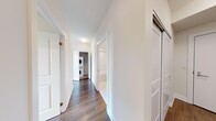 This well-appointed 2-bedroom, 2-bathroom residence offers a thoughtfully designed single-floor layout that maximizes both functionality and comfort. The open-concept kitchen is a standout feature, showcasing white cabinetry, a stone-look tile backsplash, stainless steel appliances, and a large central island with a clean white countertop — ideal for both meal preparation and casual dining. Large sliding glass doors and oversized windows flood the living and kitchen area with natural light while offering expansive views of the surrounding landscape and neighborhood.

Both bedrooms are generously proportioned, each featuring warm hardwood-style flooring and large windows that frame pleasant outdoor views. The primary bedroom benefits from a dedicated closet with built-in wire shelving for organized storage, alongside an ensuite bathroom. The two bathrooms are finished in a clean, contemporary style with large-format white tile flooring, white vanities with sleek countertops, oversized mirrors, and a shower-tub combination in the main bath.

The hallway connects the living spaces efficiently and notably includes a stacked in-unit washer and dryer, adding everyday convenience. Throughout the residence, neutral tones, crisp white walls, and wood-finish flooring create a bright, modern ambiance.