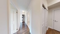 This well-appointed 2-bedroom, 2-bathroom residence offers a thoughtfully designed single-floor layout that maximizes both functionality and comfort. The open-concept kitchen is a standout feature, showcasing white cabinetry, a stone-look tile backsplash, stainless steel appliances, and a large central island with a clean white countertop — ideal for both meal preparation and casual dining. Large sliding glass doors and oversized windows flood the living and kitchen area with natural light while offering expansive views of the surrounding landscape and neighborhood.

Both bedrooms are generously proportioned, each featuring warm hardwood-style flooring and large windows that frame pleasant outdoor views. The primary bedroom benefits from a dedicated closet with built-in wire shelving for organized storage, alongside an ensuite bathroom. The two bathrooms are finished in a clean, contemporary style with large-format white tile flooring, white vanities with sleek countertops, oversized mirrors, and a shower-tub combination in the main bath.

The hallway connects the living spaces efficiently and notably includes a stacked in-unit washer and dryer, adding everyday convenience. Throughout the residence, neutral tones, crisp white walls, and wood-finish flooring create a bright, modern ambiance.