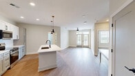 Located at 400 Universal Rd in Southern Pines, NC, this well-appointed 2-bedroom, 2-bathroom single-floor residence offers a thoughtfully designed layout with modern finishes throughout. Warm hardwood-style flooring flows seamlessly across all main living areas, creating a cohesive and inviting atmosphere.

The open-concept kitchen and living area serves as the heart of the home. The kitchen is outfitted with white shaker-style cabinetry, stainless steel appliances including a refrigerator, range, and microwave, and a large central island with a white quartz countertop, undermount sink, and stylish pendant lighting. The adjacent living area features a ceiling fan and French doors that open to a private balcony, allowing for natural light and outdoor views.

The primary bedroom is a comfortable retreat with a ceiling fan, a walk-in closet with wire shelving, and direct access to a private en-suite bathroom. The en-suite includes a single vanity with white countertop, matte black fixtures, and a glass-enclosed shower. The second bedroom also features a ceiling fan and ample natural light. A second full bathroom offers a tiled tub-shower combination with a window. Two dedicated closets provide generous storage throughout the residence.