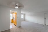 This single-floor residence offers a well-organized layout designed for comfortable everyday living. The expansive main living area is carpeted and bathed in natural light from a large window, with a ceiling fan overhead providing year-round comfort. The space flows openly, with a front entry door providing direct access to the living area.

The kitchen is efficiently arranged, featuring warm honey-toned wood cabinetry, dark granite-style countertops, a gas range, and tile flooring. A window above the counter brings in natural light and outdoor views, making the kitchen bright and functional. The refrigerator is conveniently positioned nearby.

The residence includes two carpeted bedrooms, each offering a generous footprint. The primary bedroom features a ceiling fan and direct access to a full bathroom, while the secondary bedroom benefits from natural light through a window and includes dual closets for ample storage. Ceiling fans are present in multiple rooms, contributing to a consistent level of comfort throughout.

The bathrooms are clean and straightforward in design. The full bath includes a tiled tub-and-shower combination, vanity with mirror cabinet, and tile flooring. A second bathroom provides a toilet and additional utility. Neutral tones throughout the residence create a cohesive and inviting atmosphere.