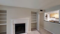Located at 4601 Baymar Dr in Raleigh, North Carolina, this single-floor home offers a comfortable and well-appointed layout designed for easy living. The living area serves as the heart of the home, highlighted by a classic white-mantled fireplace that adds warmth and a timeless focal point to the space. Adjacent to the fireplace, a set of built-in shelving units provides both functional storage and display space, enhancing the room's character. Neutral-toned walls and plush carpeting create a calm, inviting atmosphere throughout. A pass-through window connects the living area to what appears to be the kitchen, promoting an open and communicative flow between spaces. The overall color palette of soft beiges and whites lends the home a clean, move-in-ready aesthetic. The single-floor layout ensures convenient accessibility, making the entire home easy to navigate. With its combination of classic architectural details, practical built-ins, and a cohesive neutral design, this Raleigh home presents a welcoming environment suited for a variety of lifestyles.