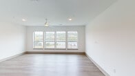 Located at 100 O Fallon Ave in Dayton, Kentucky, this single-floor unit offers a thoughtfully designed, modern interior with clean lines and contemporary finishes throughout. The open living area is a standout feature, boasting a bank of four large windows that flood the space with natural light and frame sweeping outdoor views of the surrounding landscape. A ceiling fan and recessed lighting complete the airy, comfortable feel of this main living space.

The kitchen is well-appointed with white shaker-style cabinetry, light quartz countertops, a subway tile backsplash, and a full suite of stainless steel appliances, including a range, microwave, and dishwasher. A deep undermount sink with a modern pull-down faucet adds a refined touch to this functional space.

The bedroom features warm wood-tone luxury vinyl plank flooring, a ceiling fan, a spacious open closet with built-in shelving, and clerestory windows above a sliding barn door that add architectural interest and allow light to flow between spaces.

Two bathrooms are finished with white vanities, light countertops, and wood-look flooring. One features a soaking tub with a curved shower rod, while the other offers a tub-shower combination. The consistent use of light tones, modern hardware, and durable flooring throughout creates a cohesive, move-in-ready living environment.