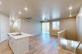 Located at 3100 N Akers St in Visalia, CA, this well-appointed 3-bedroom, 2-bathroom home offers a thoughtfully designed layout across a single level, accessed via a staircase with light wood treads and a clean white railing. The open-concept main living area seamlessly connects the kitchen, dining, and living spaces, all finished with light hardwood-style flooring that creates a bright, cohesive feel throughout. The kitchen is a standout feature, boasting crisp white shaker cabinetry, a white quartz peninsula with an integrated sink, and a full suite of stainless steel appliances including a range, microwave, and French door refrigerator. Recessed lighting and a wall-mounted mini-split system ensure comfort year-round. The living area is enhanced by a ceiling fan and sliding glass doors that open to a covered balcony, offering open views of the surrounding neighborhood under sunny California skies. The three bedrooms are carpeted for comfort, each equipped with ceiling fans and mini-split units, while the primary bedroom includes its own access door and generous closet space. The bathrooms feature white vanity cabinetry, wood-look flooring, and a sliding glass shower enclosure. Additional storage is provided by a pantry and multiple closets throughout.
