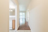 This single-floor residence offers a well-organized layout with a variety of functional spaces connected by a tiled entry hallway, which also houses the electrical panel. The hallway leads toward the main living area, where rich hardwood flooring extends throughout and a sliding glass door opens to a private balcony, filling the space with natural light and outdoor views of surrounding greenery.

The kitchen is designed for practicality and efficiency, featuring warm oak cabinetry that extends to the upper and lower levels, light-toned countertops, a double stainless steel sink, and white appliances including an electric range, over-the-range microwave, refrigerator, and dishwasher. A skylight adds brightness overhead. The kitchen connects seamlessly to the living and dining area via a pass-through counter, creating an open and sociable flow. The dining area is accented by an elegant chandelier.

The bedrooms are carpeted and offer a quiet, comfortable atmosphere, each with windows that frame lush outdoor views. The bathroom is cleanly appointed with a vanity featuring oak cabinetry, a large mirror with overhead lighting, a tub-shower combination, and tile flooring. Textured ceilings are present throughout, adding a consistent architectural detail across the entire space.
